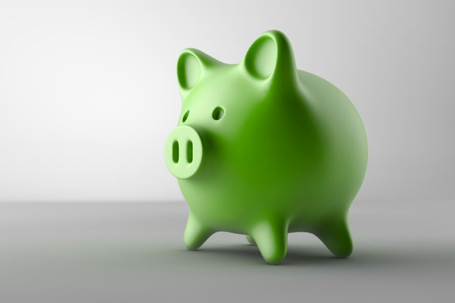 Green piggy bank on a gray counter to indicate affordable dental care in Indian Trail, NC